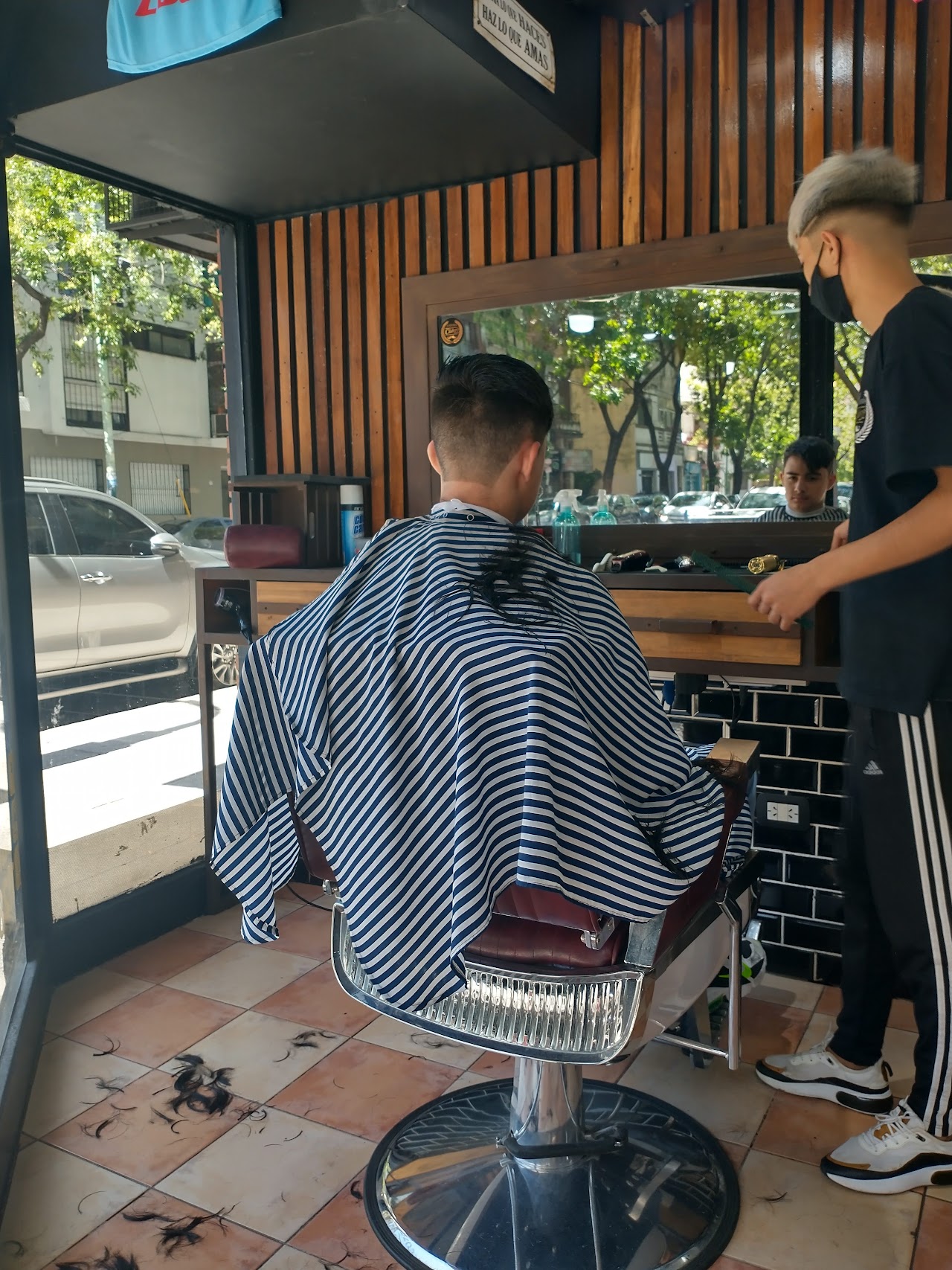Barbero cortando el cabello a un cliente dentro de Barberia Club 22